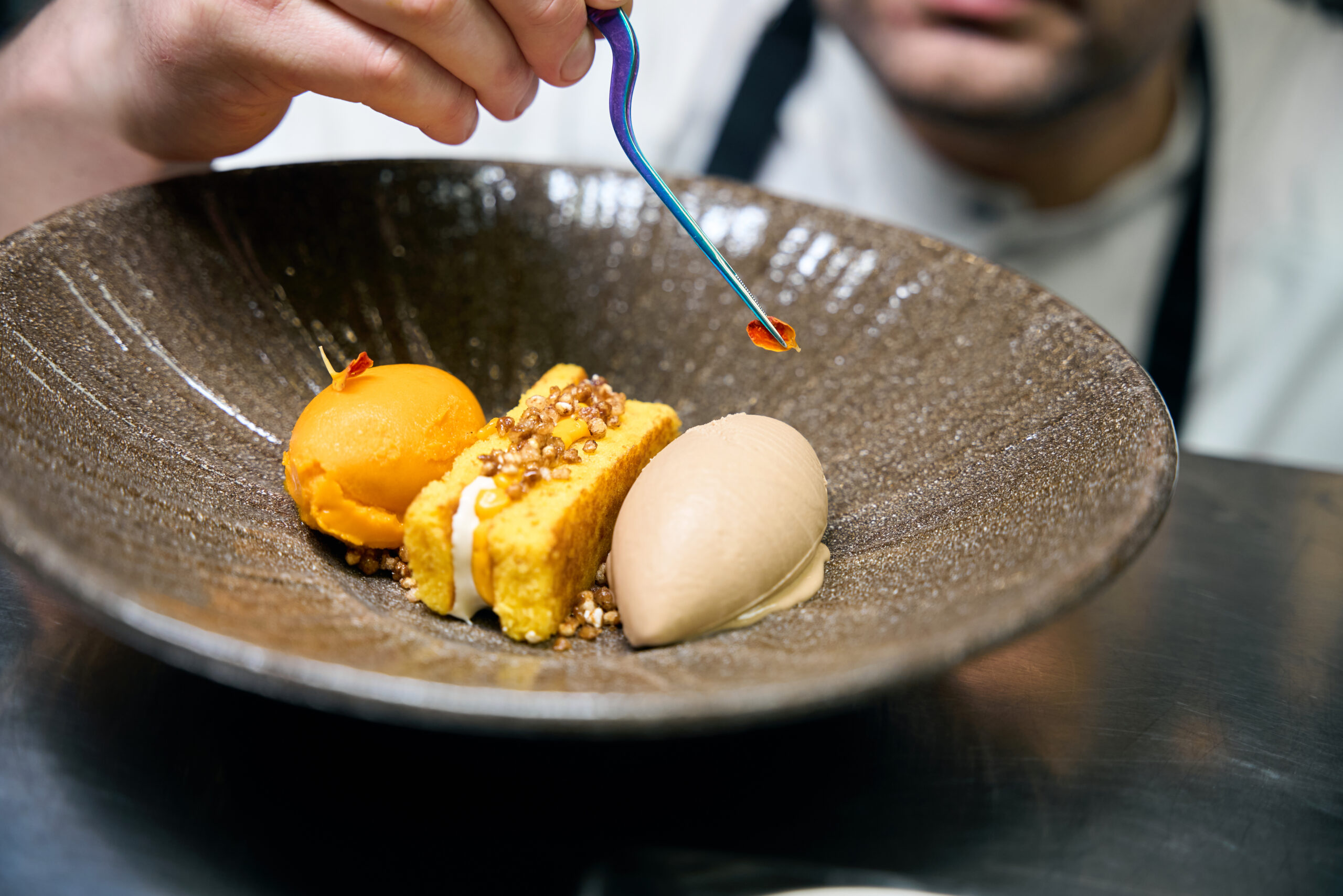 Selective focus of cropped chef hand decorating leaf with tweezers on cookie aprovisionamiento de yates, servicios náuticos Mallorca, suministros embarcaciones Baleares, logística marítima Ibiza, productos frescos yates